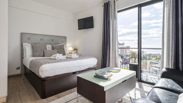 Habitación de hotel con cama, televisor de pantalla plana, una mesita de centro y balcón con vistas.