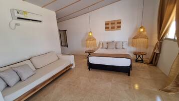 Un dormitorio con cama, sofá y lámparas colgantes.