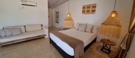 A modern bedroom with a bed, a sofa, and two hanging lamps.