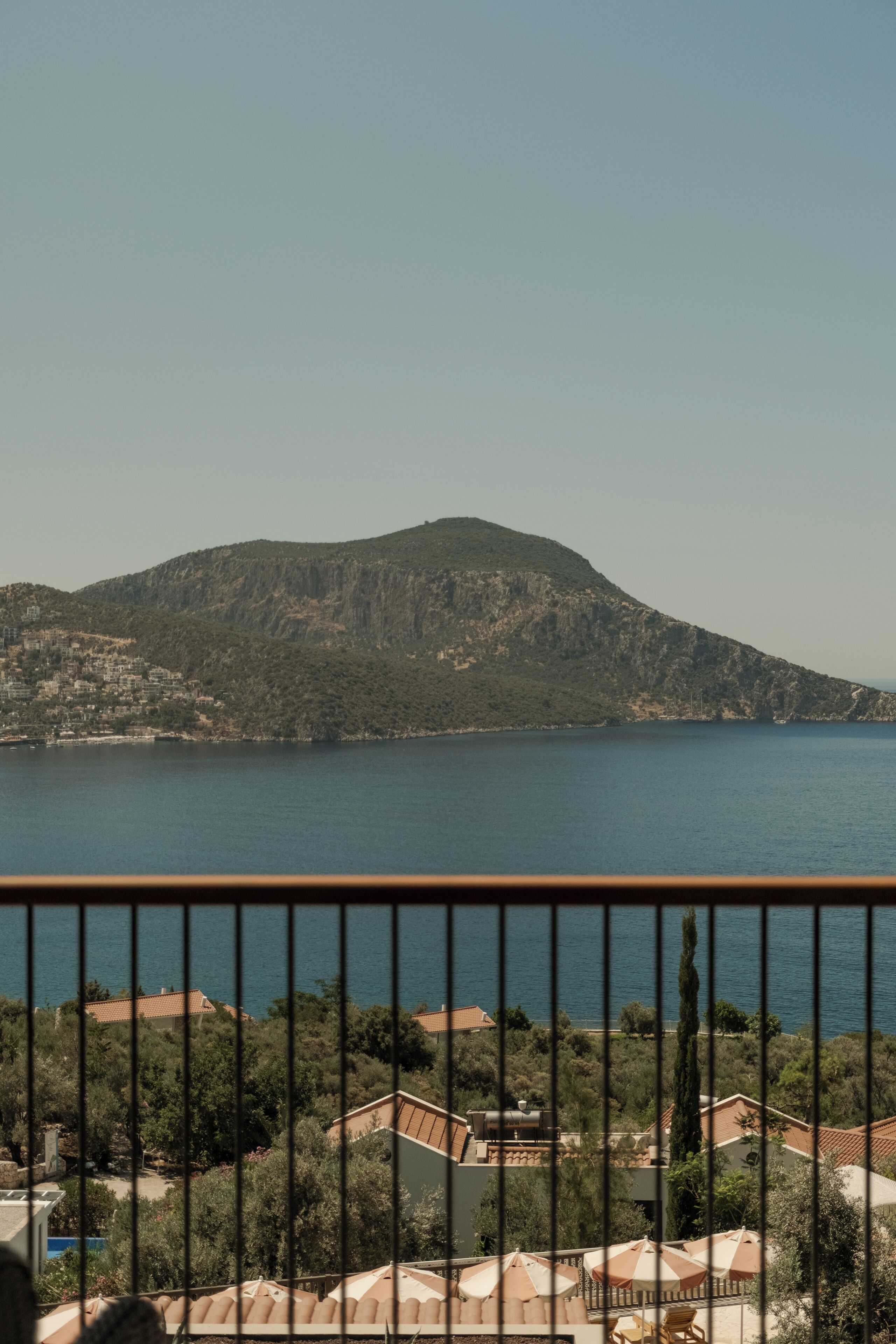 A coastal view with a mountain, a body of water, and a residential area with buildings and greenery.