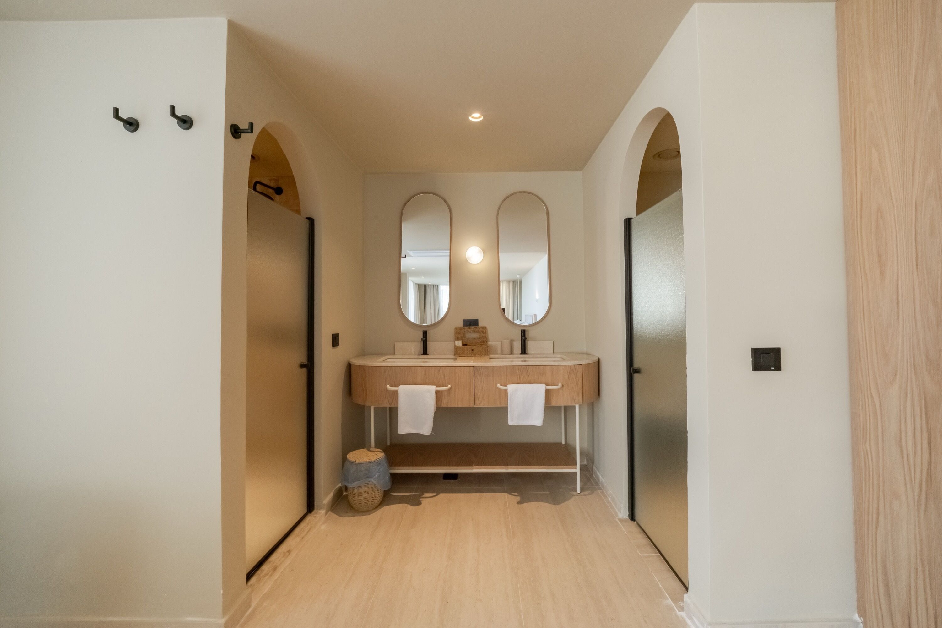 A modern bathroom with a double sink, two mirrors, and a wooden vanity.