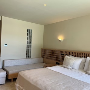 A hotel room with a large bed, a bench, a wall-mounted light, and a window with a grid pattern. - Asfiya Sea View Hotel (Kas)