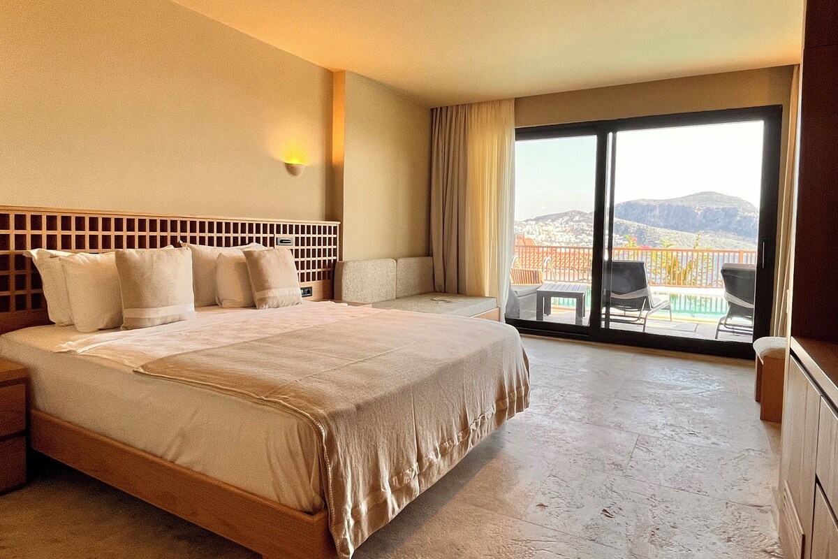 A hotel room with a large bed, a view of the city through a balcony, and a cityscape view.