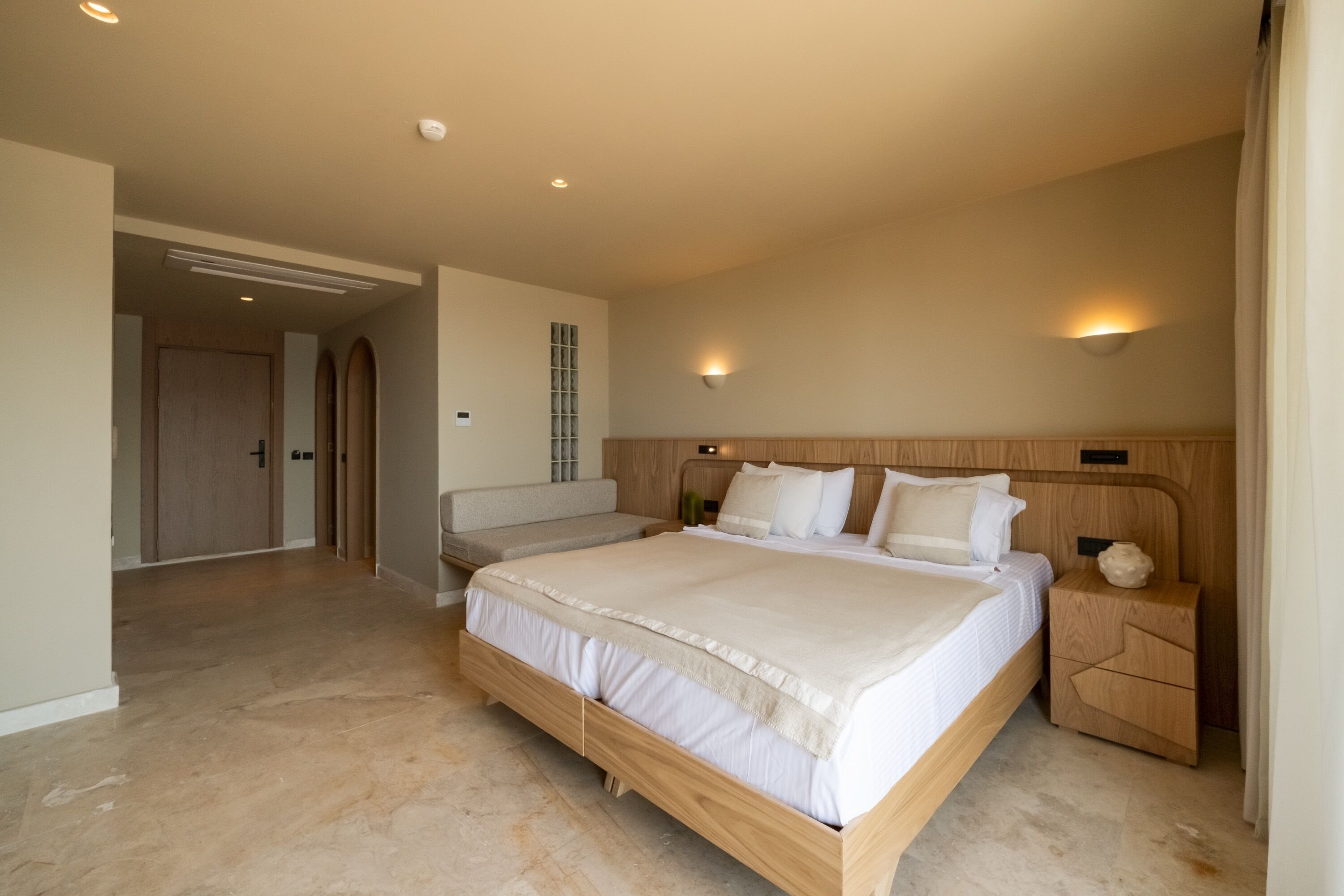 A spacious bedroom with a large bed, bedside tables, and a built-in bench.