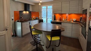 Une cuisine moderne dotée d’un îlot central, de deux tabourets de bar et d’une table à manger.