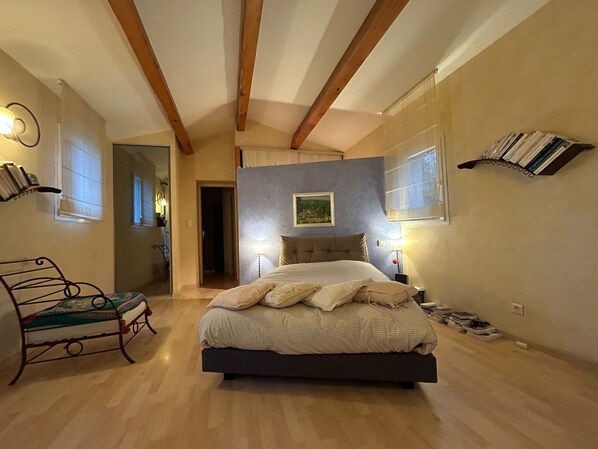 A bedroom with a bed, a chair, a bookshelf, and a painting on the wall.
