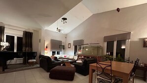 Un salon spacieux avec un piano, une table à manger et un grand aquarium.