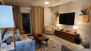 A living room with a sofa, armchair, coffee table, and a TV mounted on the wall. - Dori's Oasis: 3-bedroom house in Cocoa with WiFi, AC & Pool (Cocoa)
