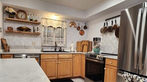 A modern kitchen with wooden cabinets, stainless steel appliances, and a tiled backsplash. - Dori's Oasis: 3-bedroom house in Cocoa with WiFi, AC & Pool (Cocoa)