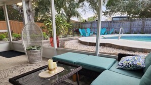 A covered patio area with a pool, outdoor seating, and a variety of plants. - Dori's Oasis: 3-bedroom house in Cocoa with WiFi, AC & Pool (Cocoa)