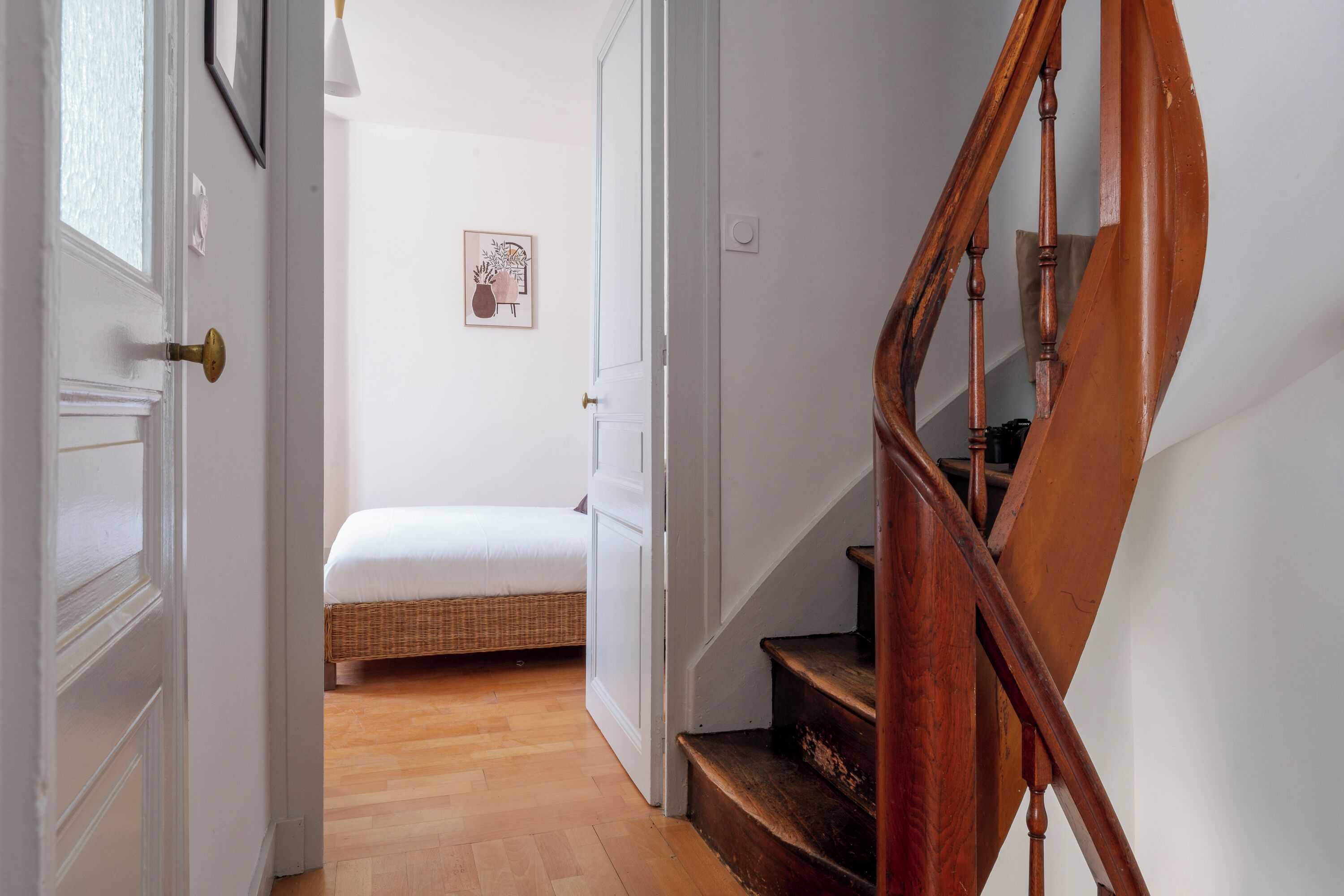 Eine Treppe führt zu einem Schlafzimmer mit einem Bett und einem Wandbild.