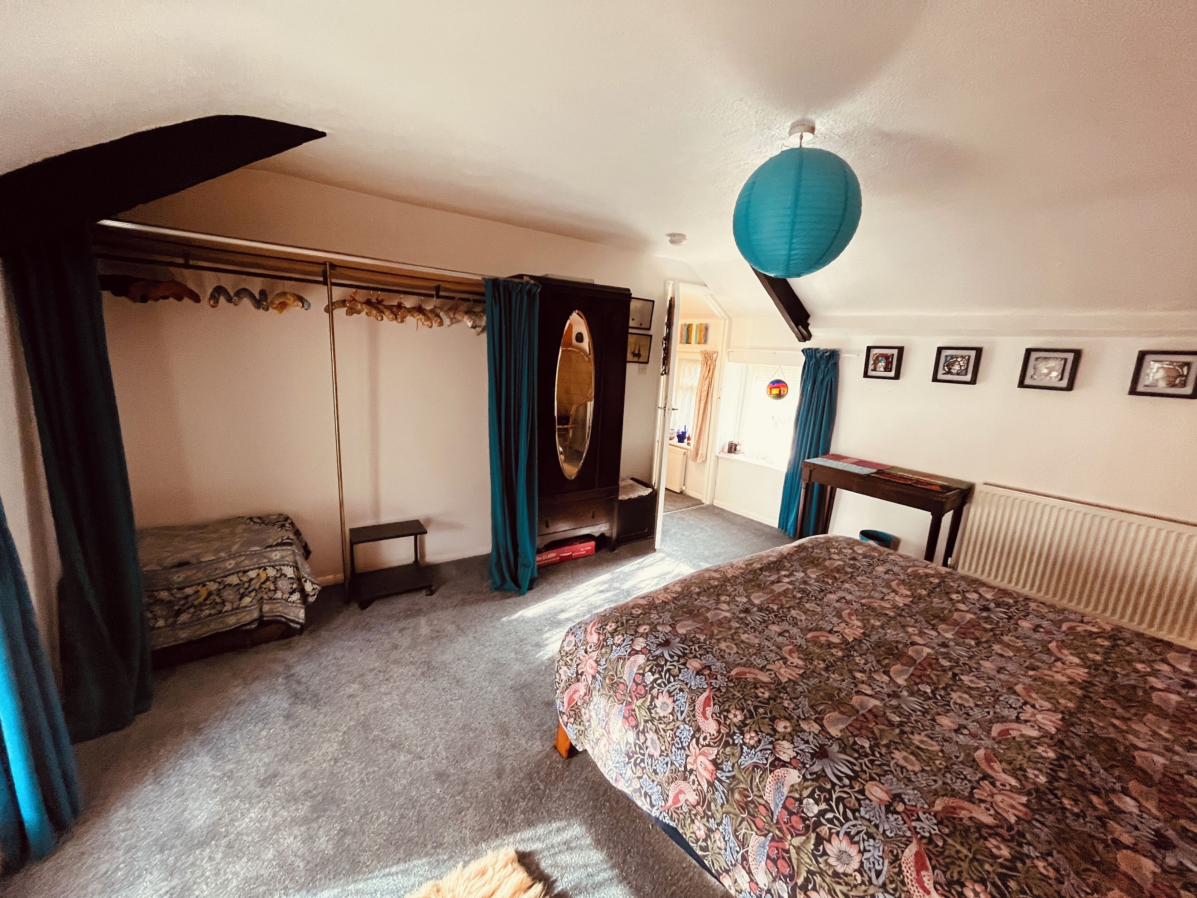 A bedroom with a bed, a dresser, a mirror, and a window with curtains.