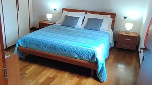 Ein Schlafzimmer mit einem hölzernen Bett, einer Backsteinwand und einer Holzbalkendecke.