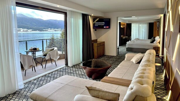 Une chambre d’hôtel avec un grand canapé, une télévision et un balcon donnant sur la mer.