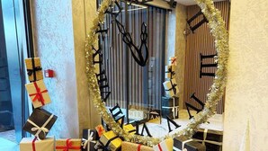 Un hall d’hôtel orné d’une grande décoration circulaire faite de guirlandes scintillantes et de lettres noires formant un message de vœux de fêtes.