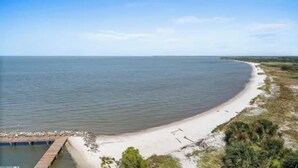 Een kuststrand met een zandstrand en een houten pier die het water in reikt.