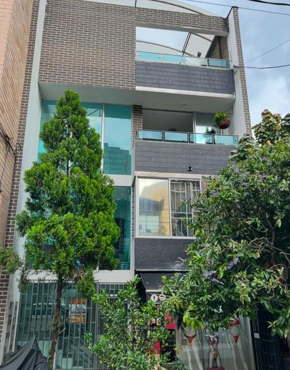 A modern building with a glass facade, multiple floors, and a balcony. - AMOBLADO LOS MOLINOS (Medellín)