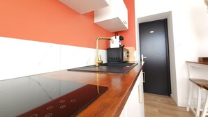 A modern kitchen with a black induction cooktop, a coffee machine, and a microwave.