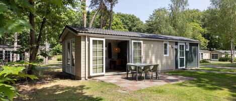 A single-story house with a patio, a table and chairs, and a door leading to a garage.
