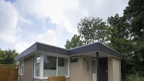 Una casa pequeña y moderna con fachada de ladrillo, un banco de madera y un patio empedrado.
