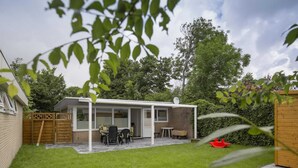 Una casa con un patio, una zona de estar techada al aire libre y un patio trasero cercado.
