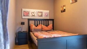 A bedroom with a bed, a nightstand, a lamp, and wall art.