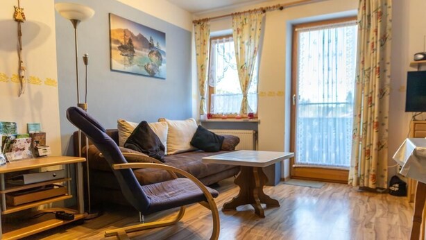 Una sala de estar con sofá, sillón mecedora, mesa de centro y televisor.