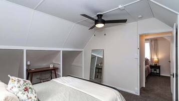 Ein Schlafzimmer mit Bett, Schreibtisch, Stuhl, Deckenventilator und Spiegel.