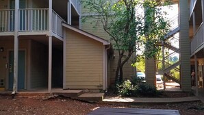A multi-story building with balconies, a central courtyard, and a tree. - Live In Lodge (Marietta)