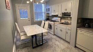Una cocina compacta con una mesa de comedor, armarios blancos, estufa a gas y horno empotrado.