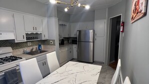 Una cocina moderna con armarios blancos, un refrigerador de acero inoxidable y una encimera de mármol.