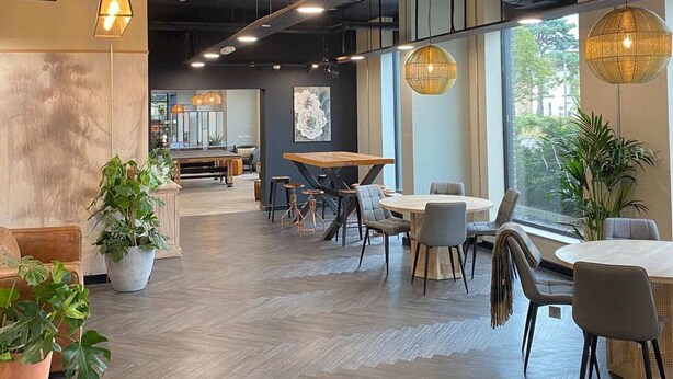 An interior with a modern design, featuring a mix of seating areas and a visible kitchen area. - Student Only Home Park (Bournemouth)