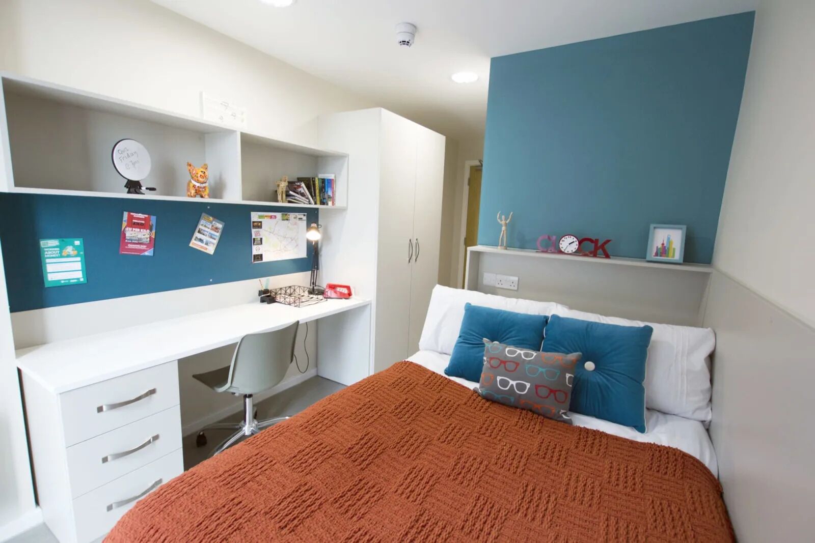 Une chambre à coucher avec un lit, un bureau et des étagères.