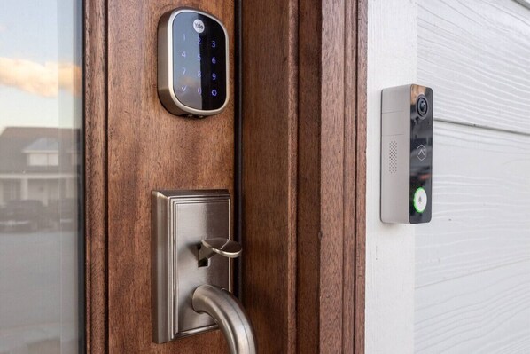 Una puerta con una cerradura inteligente Yale y un teclado, además de un sistema de intercomunicación instalado en la pared.