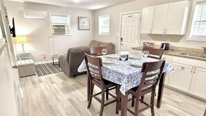 A compact living space with a dining area, kitchenette, and a sofa.