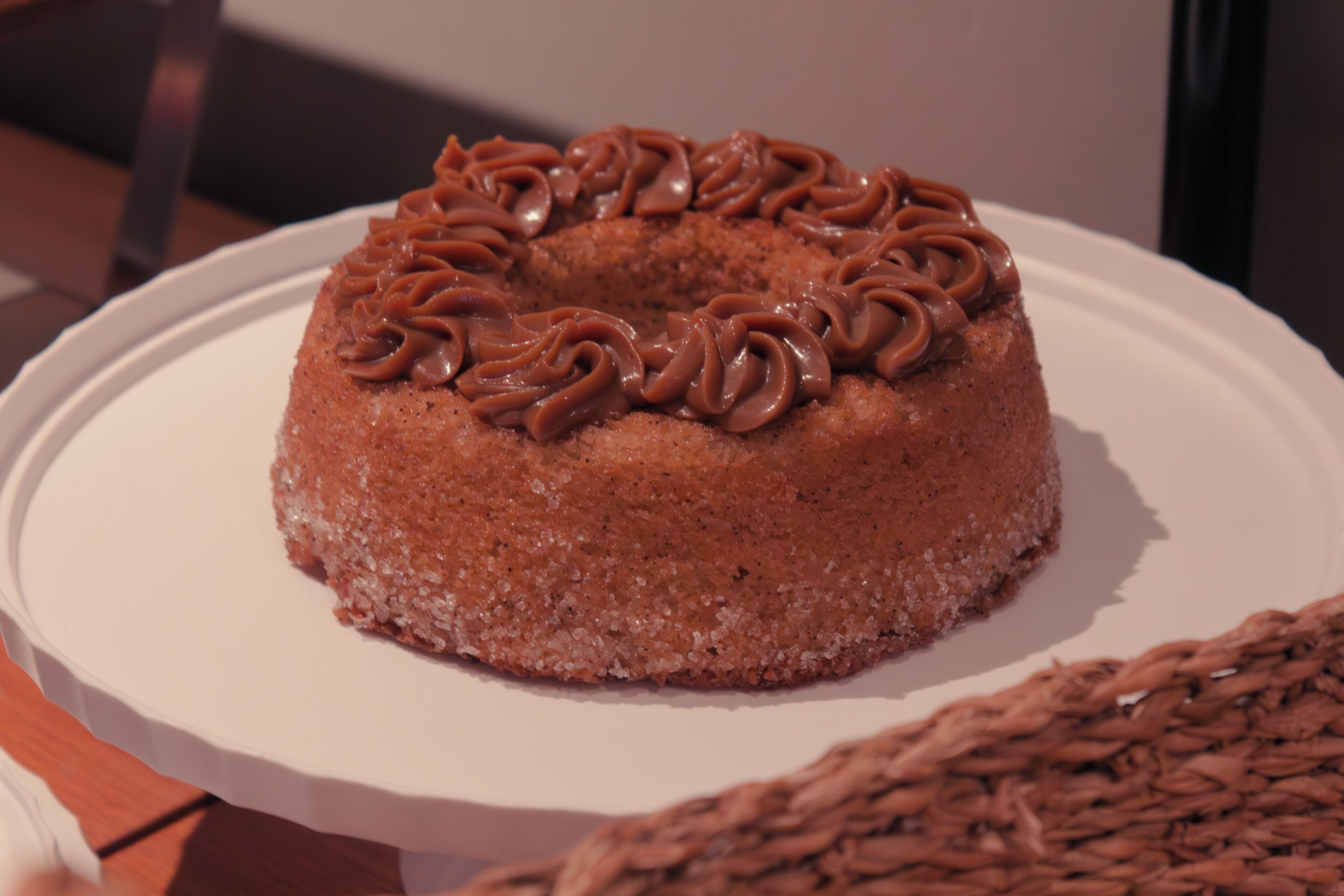 A round cake with chocolate frosting on a white plate.