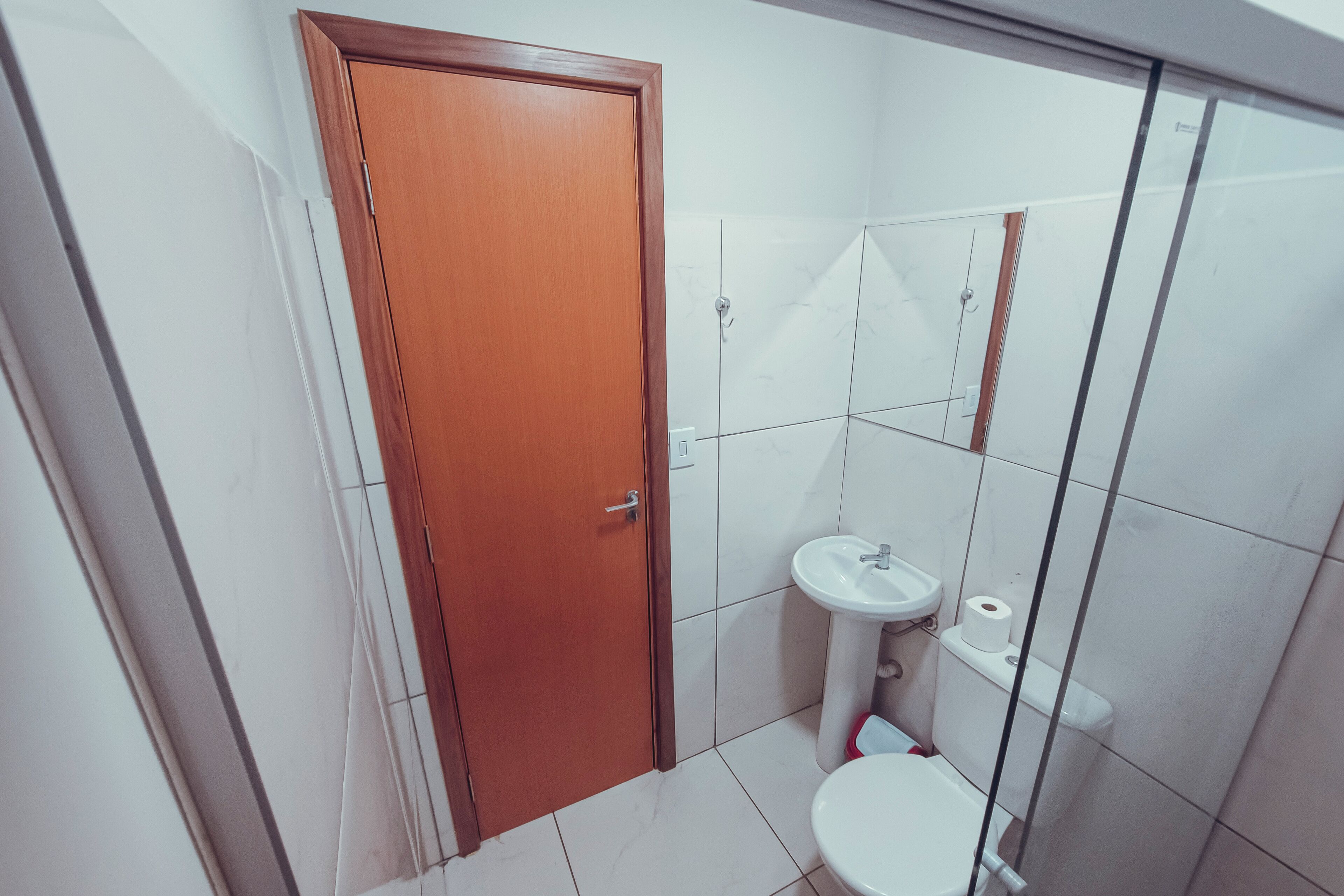 Une petite salle de bain avec une porte en bois, un lavabo blanc et des toilettes.