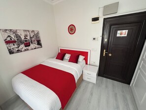 A bedroom with a bed, a nightstand, a red and white headboard, a door, and a wall-mounted artwork. - Istanberry - Scarlet Apartments (Istanbul)
