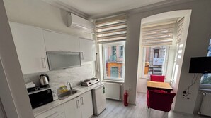 A compact kitchen with a microwave, kettle, and stove, a small sink, and a fire extinguisher. - Istanberry - Scarlet Apartments (Istanbul)