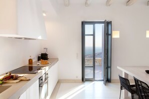 A modern kitchen with a large window, a dining area with a table and chairs, and a view of the city. - Houses G Y in Kardiani Tinos (Tinos)