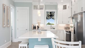 A modern kitchen with white cabinetry, a central island, stainless steel appliances, and a window with a view.