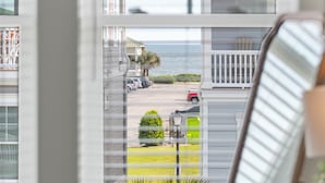A view from a window overlooking a parking area with a building and a body of water in the distance.