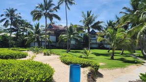 Un resort con un césped cuidado, palmeras y un edificio de techo rojo.