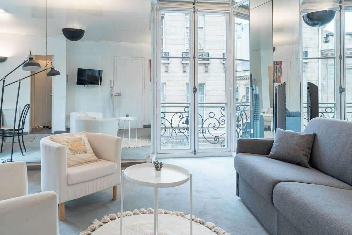 Ein modernes Wohnzimmer mit einer Couch, einem Sessel und einem kleinen runden Tisch.
