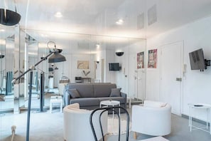 A modern living room with a grey sofa, white armchairs, a coffee table, and a floor lamp.
