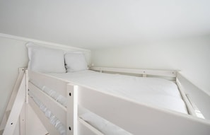 Un llit superposat blanc amb dos almoinos, un reposacapses blanc i un matalàs blanc.