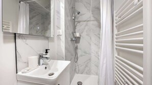 Baño con lavamanos blanco, espejo y ducha.
