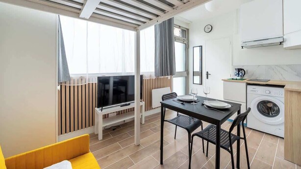 Un espacio habitable funcional con comedor, lavadora y televisión.