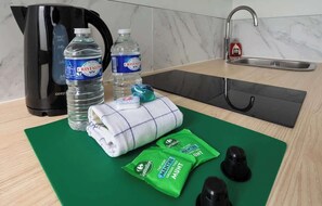 A kitchen with a coffee maker, two bottles of water, a towel, and a cutting board with food items.