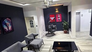 A modern living room with grey sofas, a black coffee table, and a hanging chair. - 99 Mozilla Apartments (Abuja)